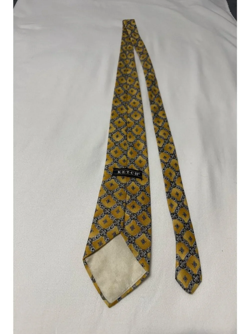 This is a vintage Ketch geometric medallion silk necktie, featuring a distinct g